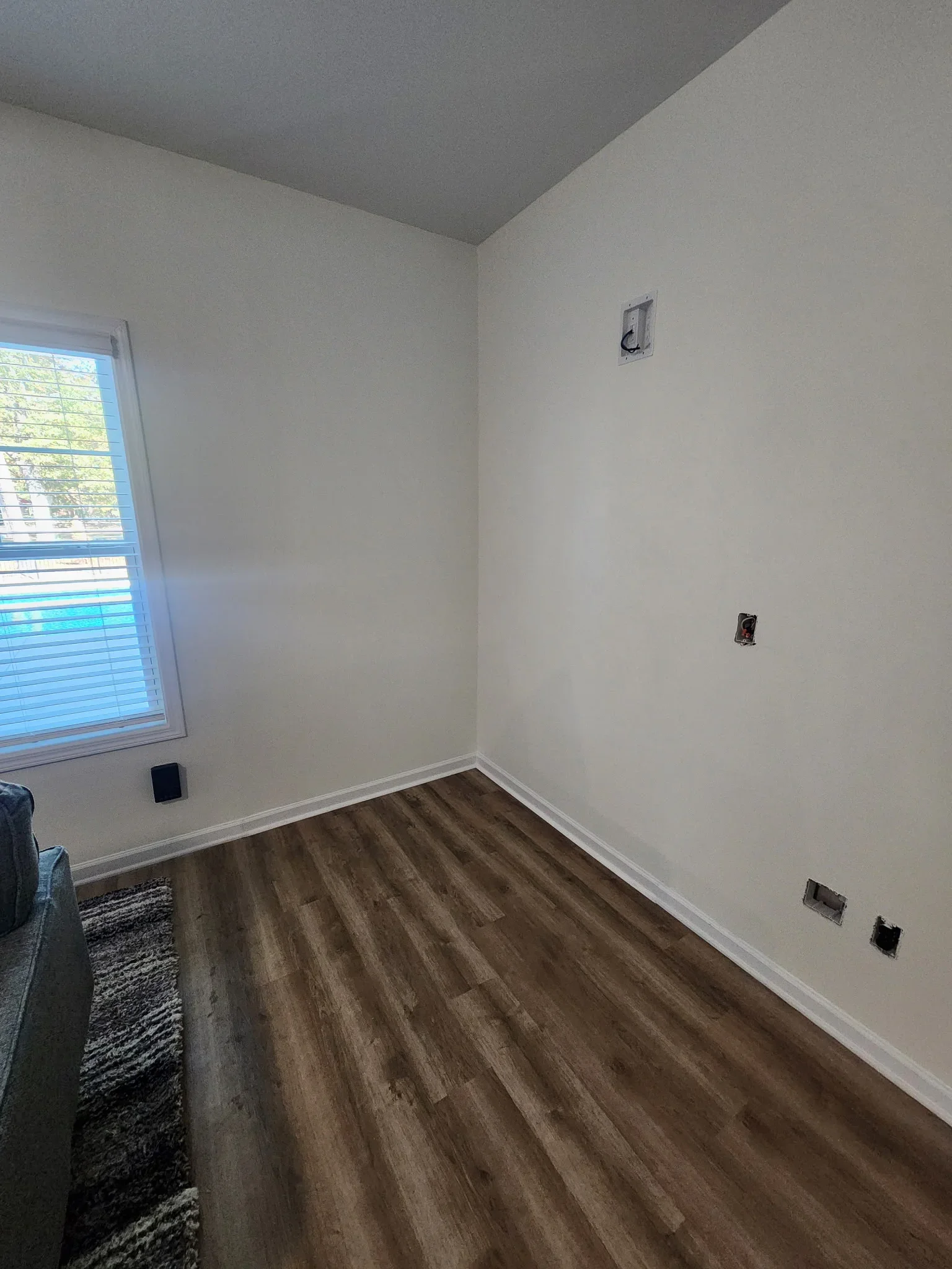 Bedroom with luxury vinyl plank flooring, white drywall walls, vaulted ceiling, and electrical outlets