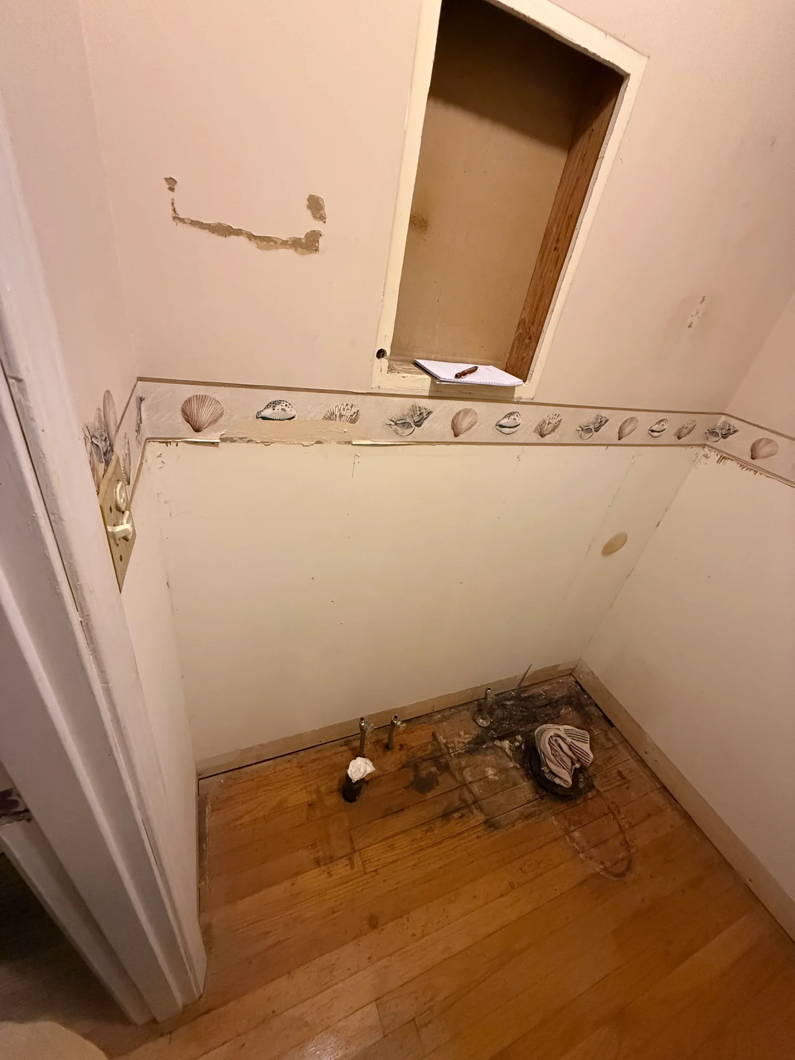Bathroom with repaired drywall, seashell tile border trim, and restored hardwood flooring